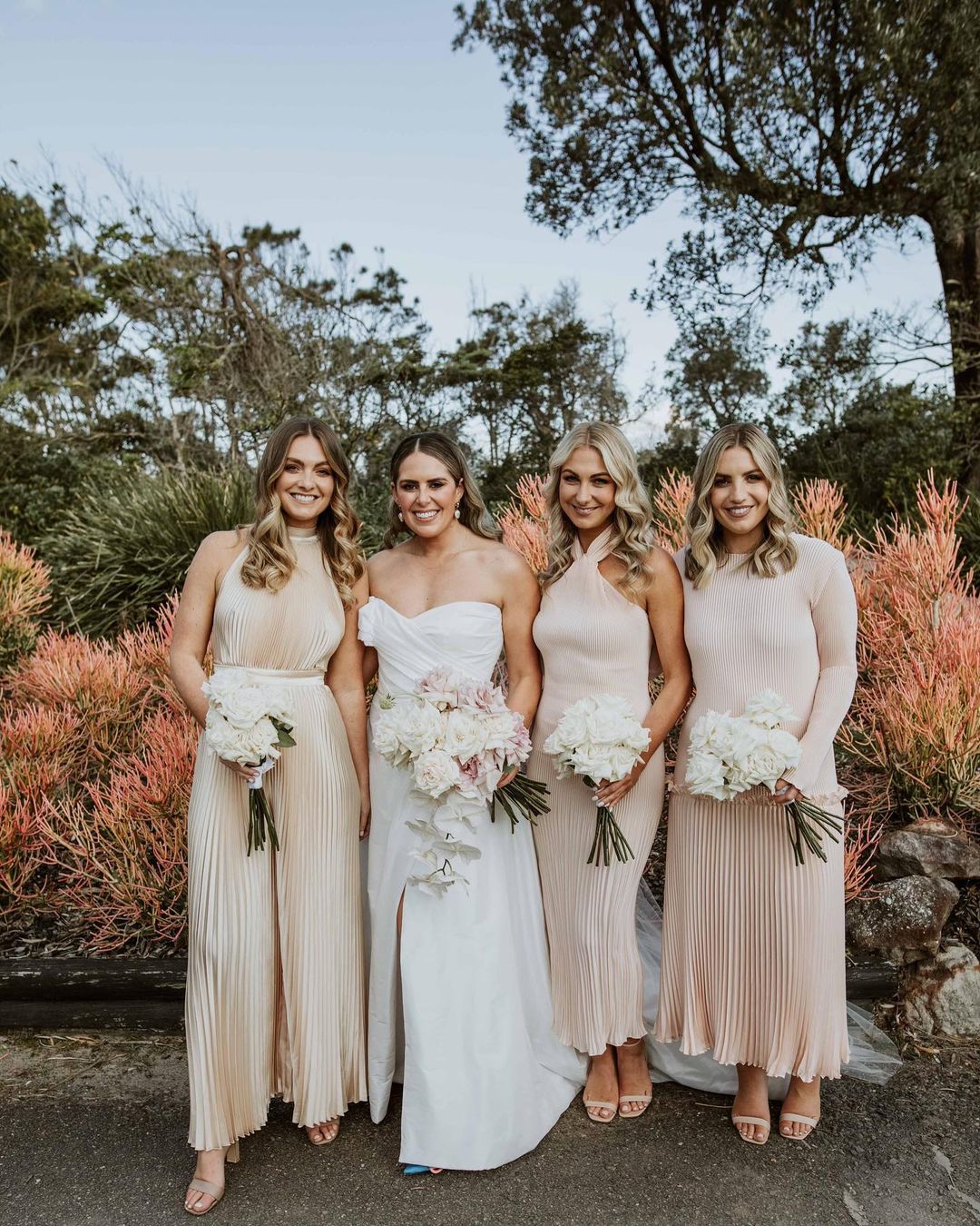 Group of bridesmaids in blush dresses posing for a picture.