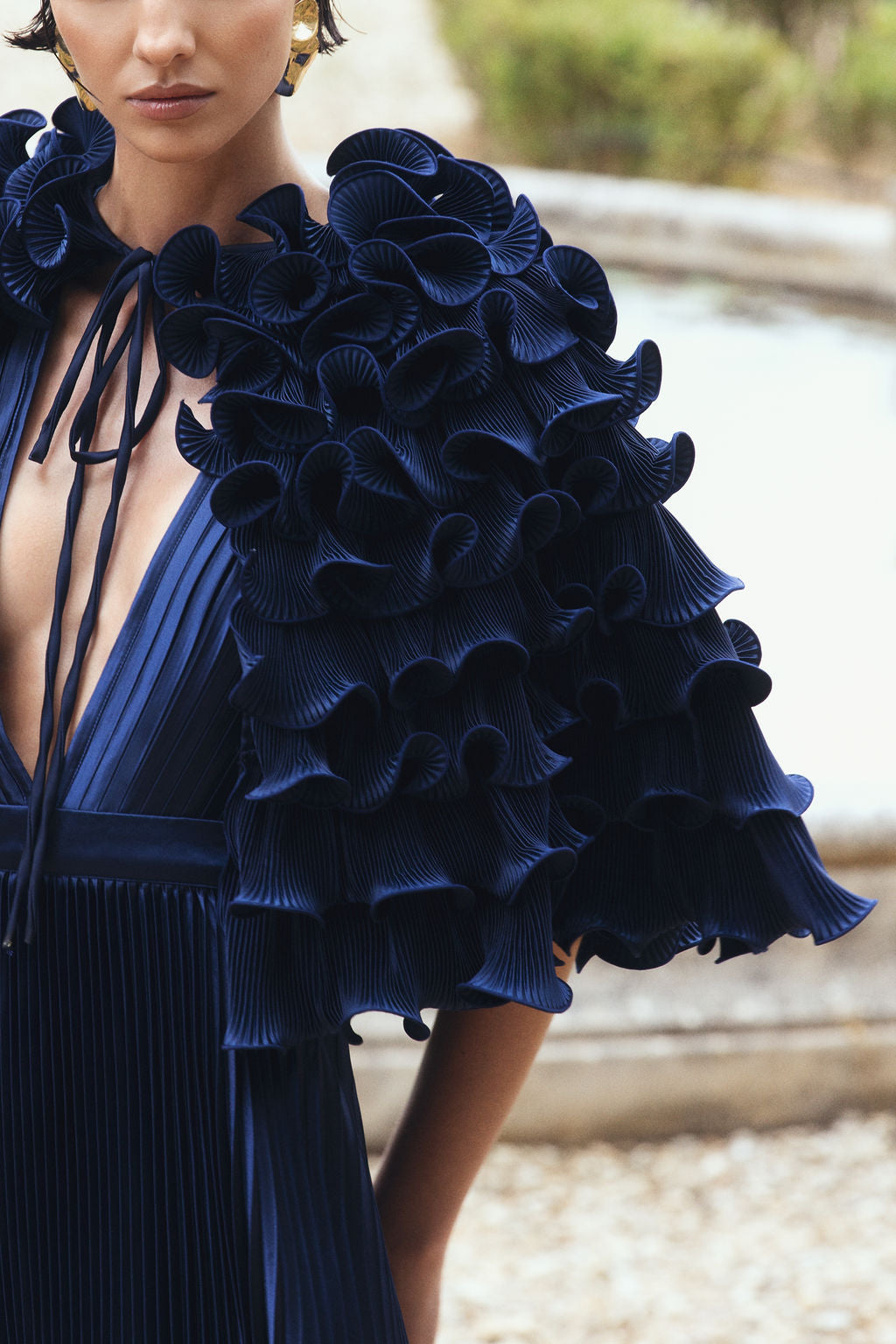 Model in a navy pleated dress with ruffled sleeves